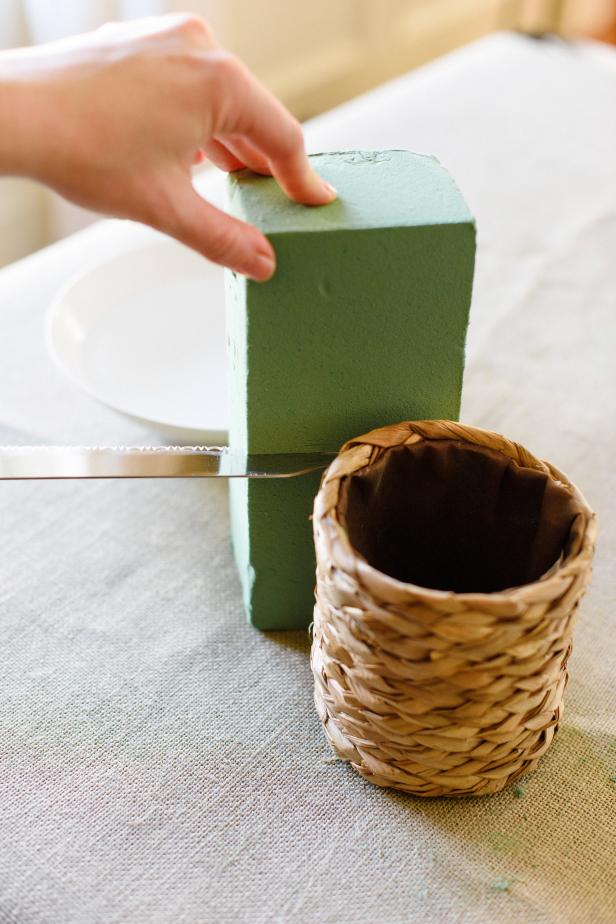 Use the knife to cut the block of floral foam in half. Shape the foam to match the shape of the basket by gently squeezing on of the halves with your hands.