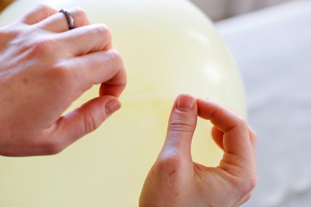 With your friend still holding the balloon, place a piece of double sided tape on the top of the balloon.