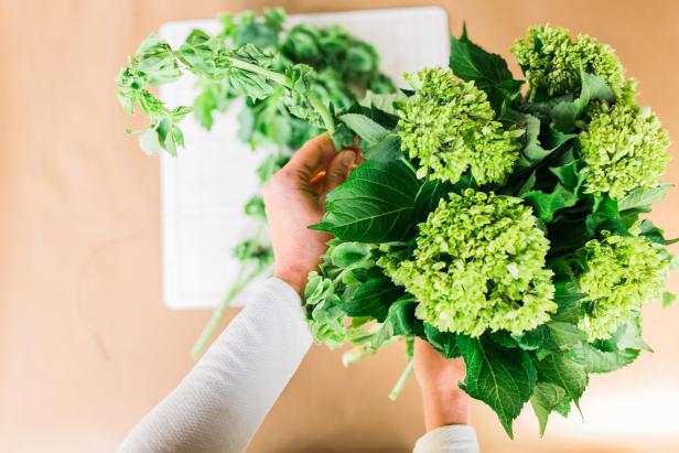 Create a tight, tone-on-tone arrangement by cutting two bunches of bells of Ireland to size with floral shears along with two bunches of your preferred green flower. By keeping the colors all the same, attention won’t be detracted from the lime wheels inside of the vessel.