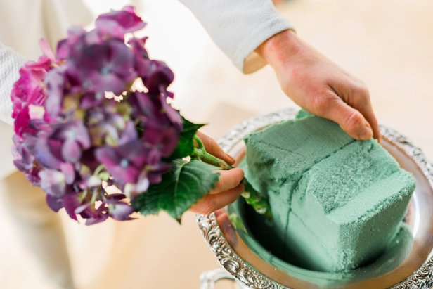 Once you’ve decided which of your flowers will sit along the top of the urn, go ahead and cut them to size with floral shears; then place them into the floral foam just above the edge of the urn. This will become the bottom row of flowers for the arrangement.