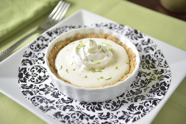 Highlight the bright flavor of key limes with this miniature version of a classic dessert. For the crust, you'll need: 1 ½ cups graham cracker crumbs, 2 tablespoons melted butter and 2 tablespoons granulated sugar. For the filling, you'll need: ½ cup fresh key lime juice, 2 cups whipped topping - plus more for garnish, 1 additional key lime for zest and 1 drop of green food coloring (optional).