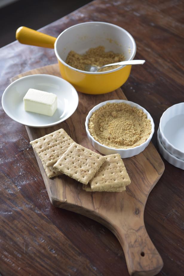 Melt the butter in a small saucepan. Add the graham cracker crumbs and sugar to the melted butter. Divide this mixture among four ramekins or other small dishes, pressing gently along the sides and bottoms to form a crust.