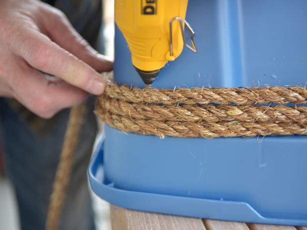 Cover the entire exterior surface of the plastic bin by wrapping the jute or sisal rope around it, then securing it in place with hot glue. Allow each layer to slightly overlap the other. This will ensure proper coverage without exposing the plastic.
