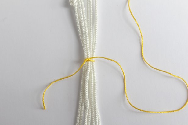Gather all 8 strands and tie a piece of the yellow rope around them all. Wrap the yellow rope around the white ropes, creating a stripe. This is the same technique as step #3.