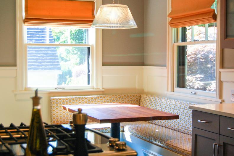 Banquette, Orange Roman Shades & White Wainscoting in Gray Kitchen