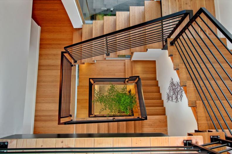 Wooden Staircase With Black Railing Spirals Down Several Floors