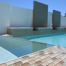 Contemporary Pool With Brown Mosaic Tile and White Stone Walls