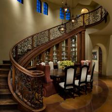 Curved Staircase Wraps Around Mediterranean Dining Room