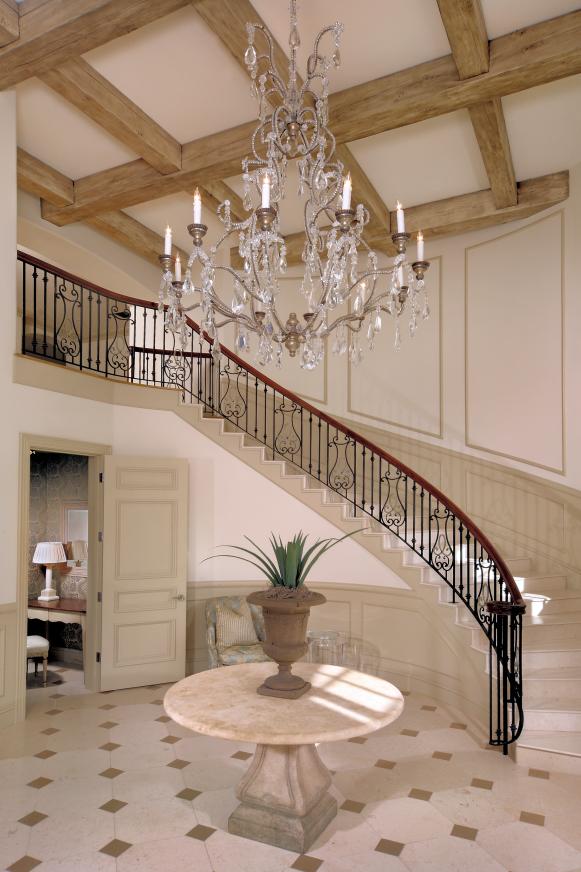 Neutral Foyer With Curved Staircase and Crystal Chandelier