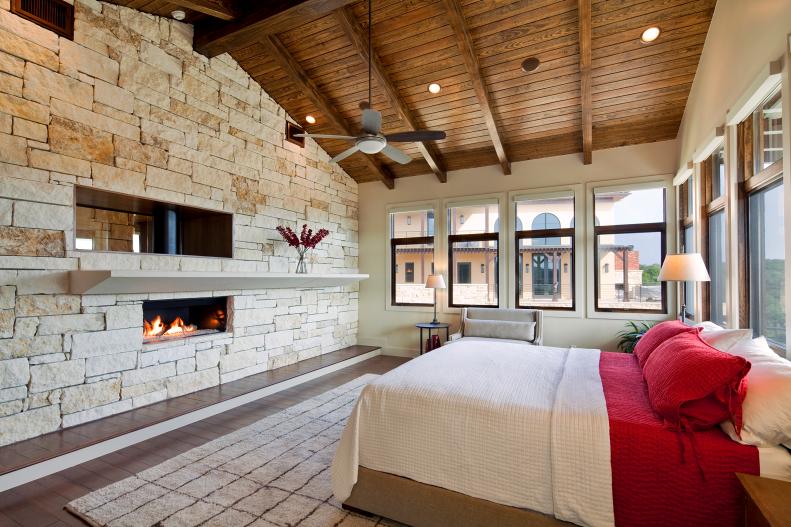 Bedroom With Angled Wood Ceiling, Stone Accent Wall and Fireplace
