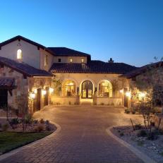 Gorgeous Home Exterior With Neutral Brick Driveway, Arched Entryway and Stone Walls