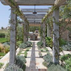 French-Inspired Home With Rustic Pergola and Stone Walkway