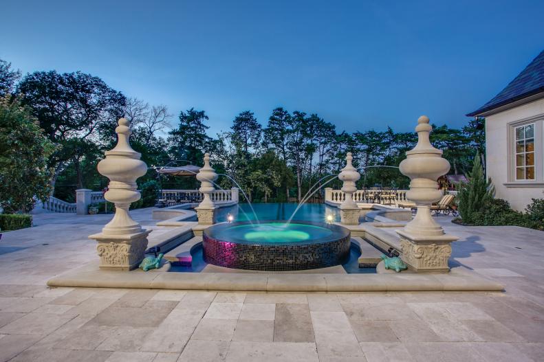 Outdoor hardscape features infinity pool and large fountain.
