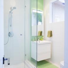 White Contemporary Bathroom Features Stylish Green Glass Accent Wall & Chic Floating Vanity