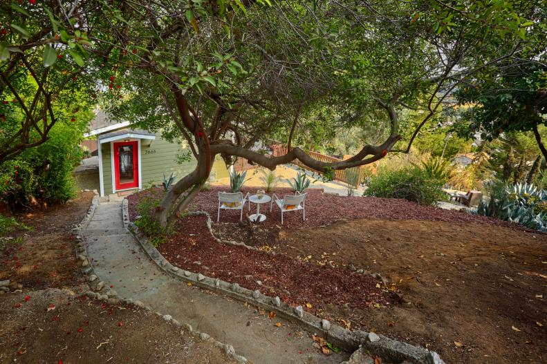 Concrete Pathway Leading to Small Green Home With Red Front Door