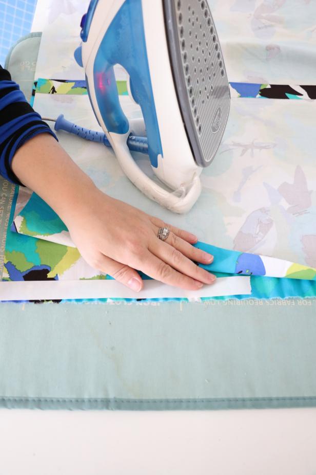 Now youâre going to use the hemming tape to iron all four edges together. Put a strip of hemming table in between both layers of fabric right against the edge. Press with a hot iron for a few seconds. Continue around the square until all the edges are âhemmedâ with the tape.