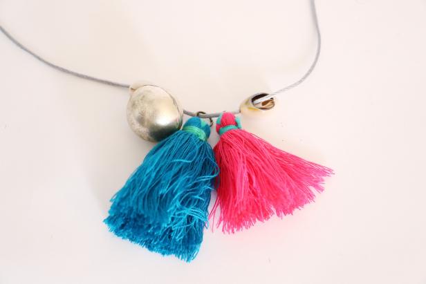 Thread everything that will be at the center of your necklace first. I used two tassels, two bells, and two shells. To keep all of these from moving around on your necklace, bring both ends of the cord up through one bead. This bead will hold everything in place.
