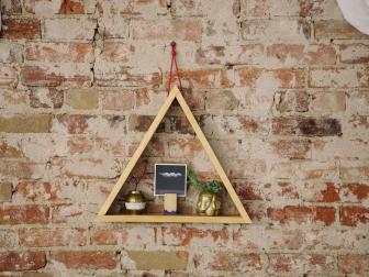 triangle wood shelf hanging on a brick wall