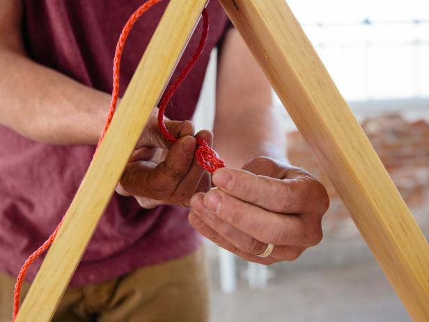 Tie a knot at the end of the rope to create a loop for hanging a wood shelf.