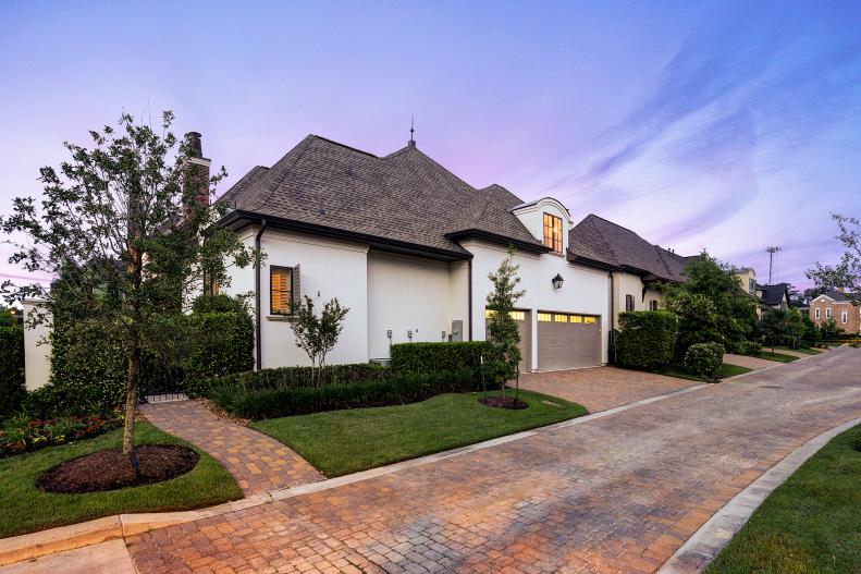 White Home Exterior With Tan Garage Doors and Brick Driveway