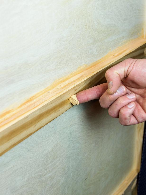 Add 1”x4” trim boards to the bottom to serve as a baseboard for the project. Sink nail heads slightly with a nail set. Fill any small gaps and the nail head hole with wood putty.