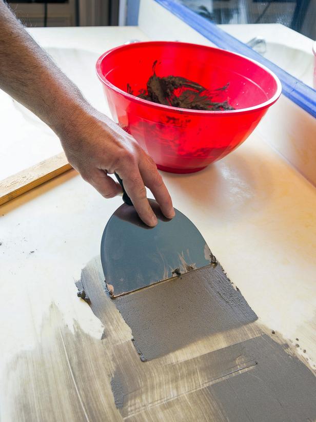 Apply the first coat to the countertop by scraping it into the sanded surface with your drywall knife. This should be a very thin coat. It is meant only to attach to the surface and make a base for additional coats.