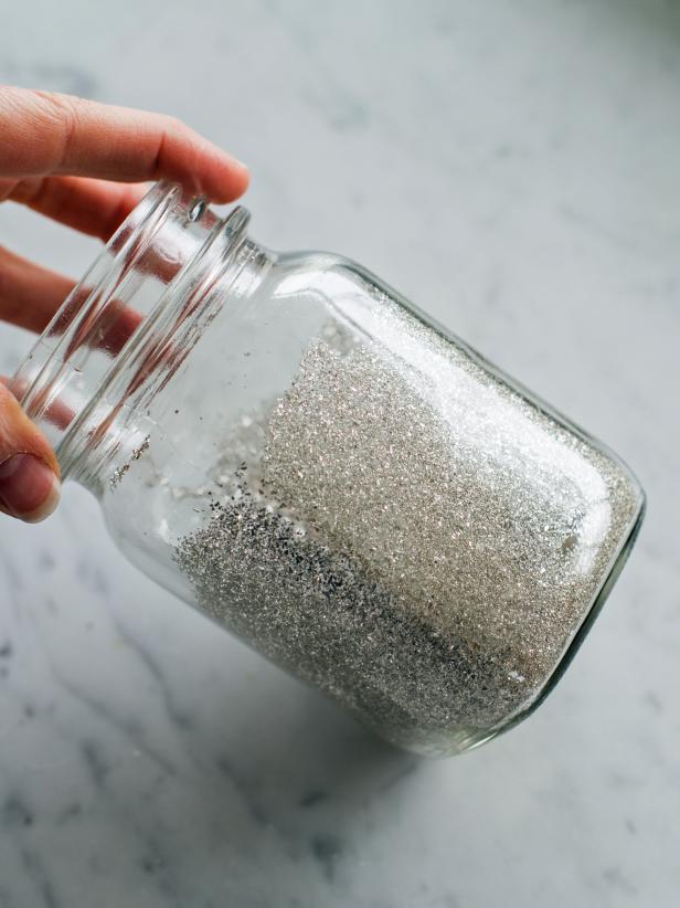 Roll jar around to allow glitter to coat all of the areas where glue was applied. Pour excess glitter back into the container to be reused.