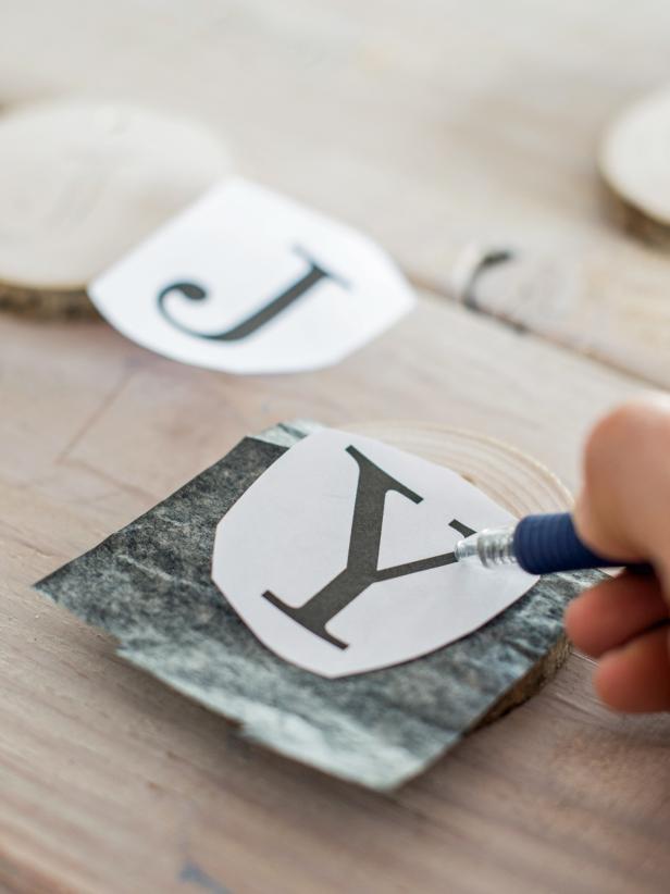 Print text and images from a computer sized to fit wood slices. Cut out each letter and images with scissors. Cut a piece of transfer paper to size as well. One piece of transfer paper can be used for all wood slices.