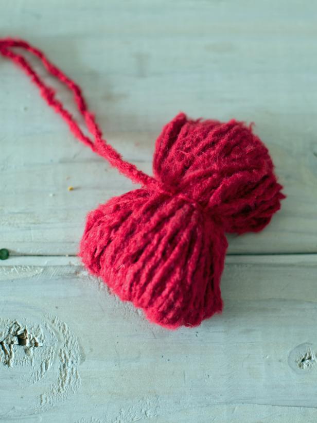 Once yarn is tied, it should be in a &quot;bow-tie&quot; shape. Cut loops on each end of the &quot;bow-tie&quot; to make a pom-pom shape. Yarn can then be trimmed, so the pom-pom is a nice, round shape, or it can be left shaggy.