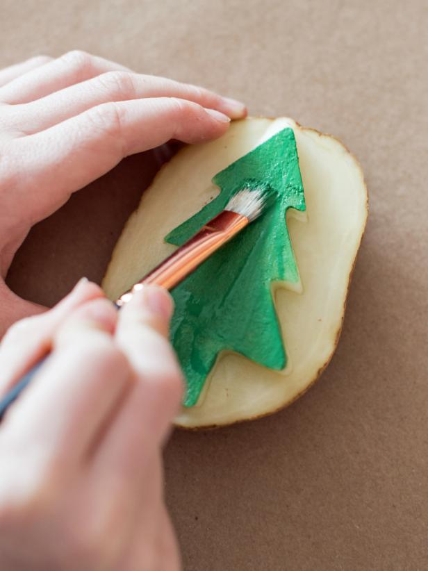 Use half-inch artist brush to paint raised design on the potato. Brushing the acrylic paint on makes the design more even, as opposed to pressing the potato directly into paint.