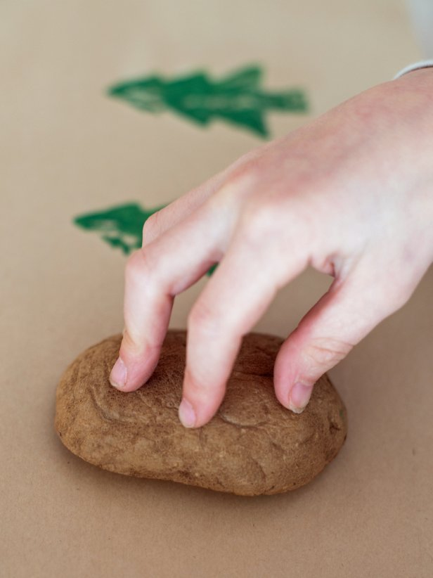 Use half-inch artist brush to paint raised design on a potato. Brushing the acrylic paint on makes the design more even, as opposed to pressing potato directly into paint. Press potato onto paper and pick it straight up, so design doesn't smear. Repeat to make an overall pattern on the paper. Brush on more paint as needed. Allow paper to full dry before using a wrap presents.