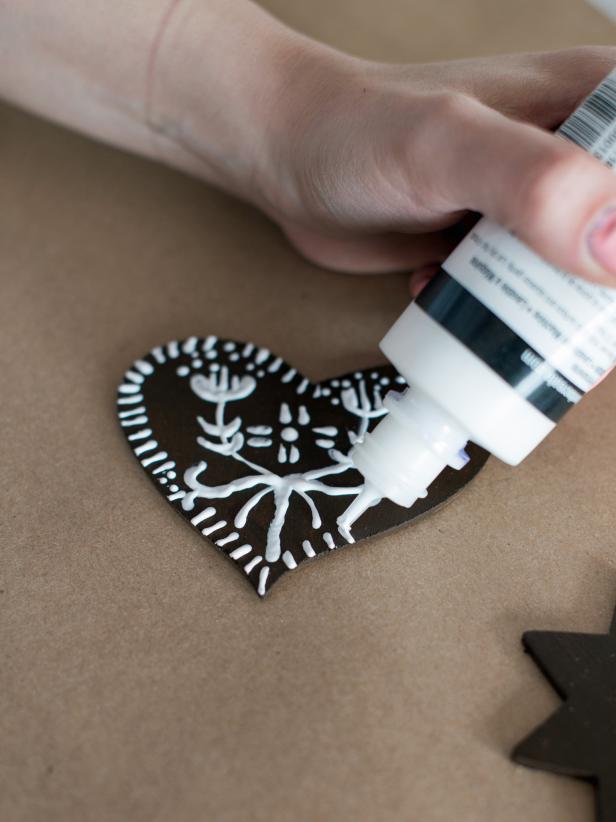 Decorate ornaments with white puff paint to simulate icing on a gingerbread cookie. Allow to fully dry before decorating second side.