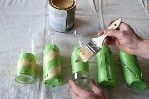 Apply gold paint to taped bottles to make a centerpiece.