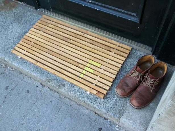 monogrammed wood doormat placed next to brown leather shoes