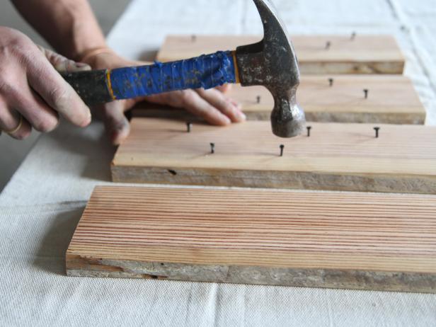 Dan Faires hammering carpet tacks into wood planks