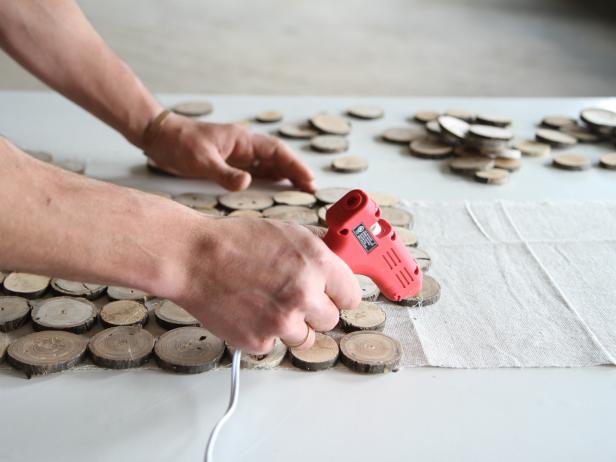 Continue attaching wood slices to the drop cloth using a hot glue gun.