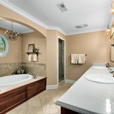 Elegant Transitional Bathroom Features Double Vanity, Welcoming Bathtub & Chandelier