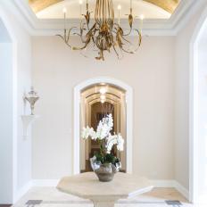 Glamorous, Symmetrical Entryway Features Illuminating Gold Ceiling & Chandelier