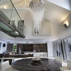 Modern Dining Room Featuring Chocolate Brown Marble Table and White Chairs Under a Hanging Modern Water-Like Feature