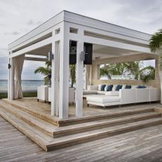Modern Cabana With Large Leather Sectional, Turquoise Throw Pillows and Surrounding Wooden Deck 