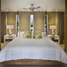 A Gorgeous Contemporary Tropical Bedroom With Rope Twist Bed Posts, Neutral Plant Wallpaper and Palm Leaf Accent Pillows