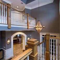 Mid-Staircase View of Transitional Foyer With Charcoal Gray Walls, Thick Wood Stair Columns and Purple Tinted Runner 