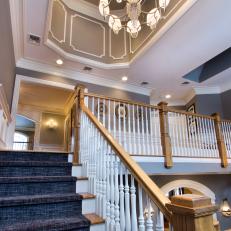 Mid Stair View of Deep Tray Ceiling With White Frame Design Over Gray Paint and Surrounding a Lampshade Chandelier 