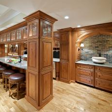 Timeless Traditional Basement Bar With Oak Cabinets, Marble Counters & Handsome Barstools
