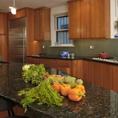 Modern Kitchen with Walnut Cabinets, Stainless Steel Refrigerator, Pendant Lights and Kitchen Island with Black Marble Top