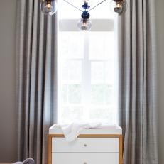 White Changing Table with Wood Trim and Modern Light Fixture in Neutral Modern Nursery