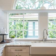 Crisp White Kitchen Features Farmhouse Sink, Subway Tile & Arched Window