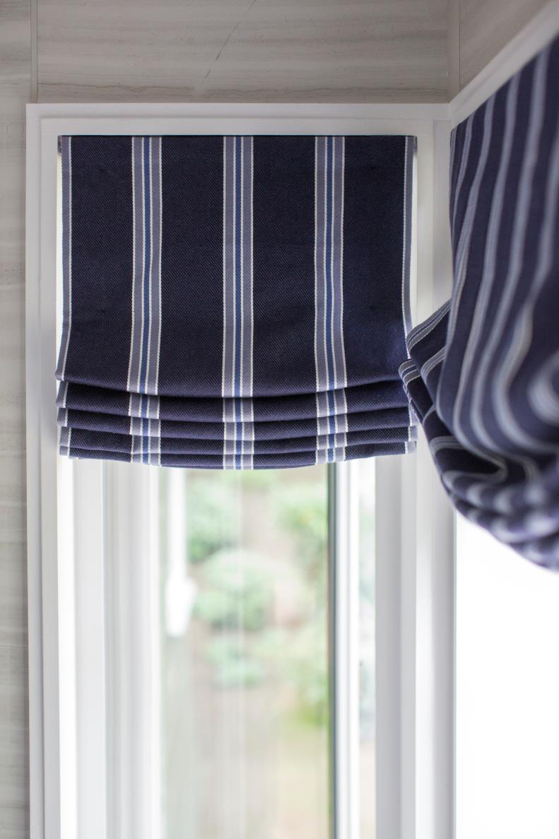 “I love a modern bathroom, just because it’s so simple,” says interior designer Brian Patrick Flynn. By adding custom roman shades in a classic blue stripe, the room is elevated to a warm and inviting space. 