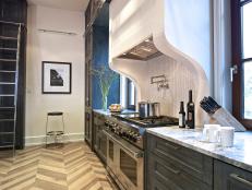 Joel Kelly Design made the most of a small kitchen thanks to a steel-and-glass wall, chevron-patterned floor and deep blue cabinets. A sliding track ladder that extends all the way around the kitchen makes it easy to reach items in the upper cabinets.