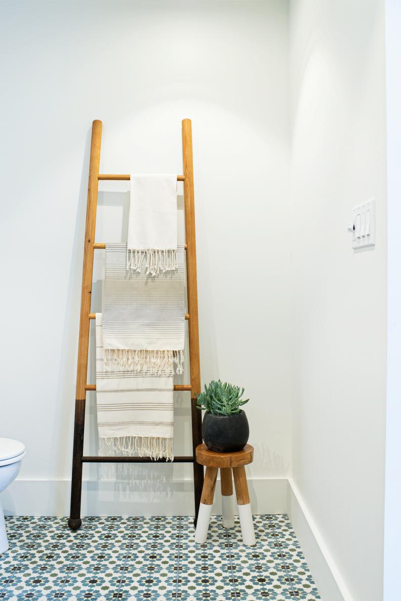 White Bathroom With Blue Tile Floor and Decorative Wood Ladder